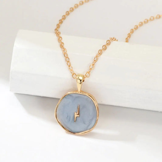 Necklace with a blue pendant and gold chain on a white background