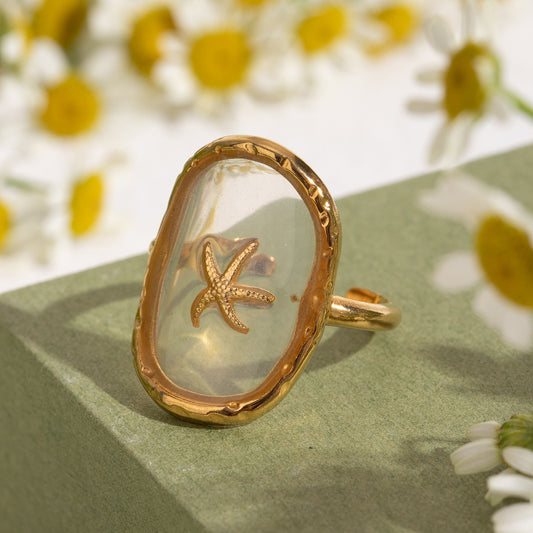 Close-up A gold-colored open ring with an adjustable band featuring a starfish design in the center