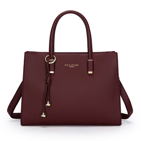 Burgundy handbag with gold accents on a white background