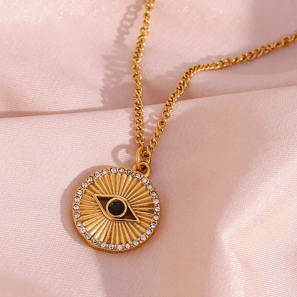 Gold necklace with an eye-shaped pendant on a pink fabric background