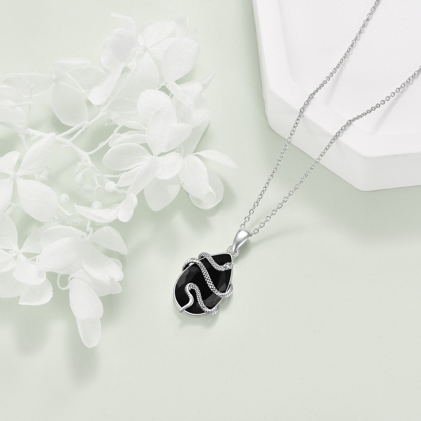 Silver necklace with a black pendant on a light background