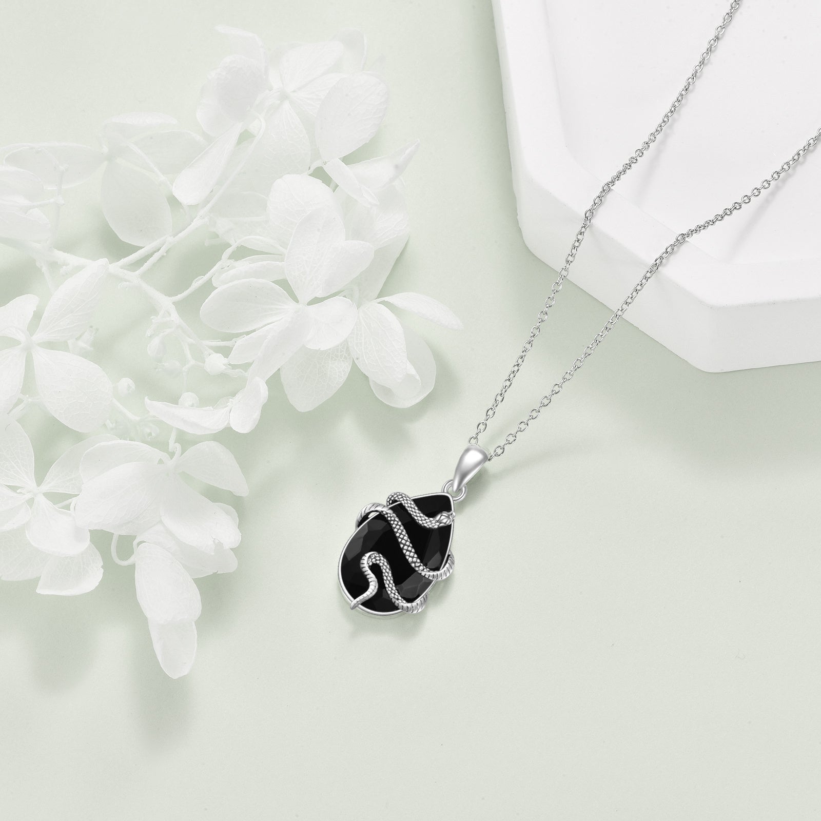 Silver necklace with a black pendant on a light background