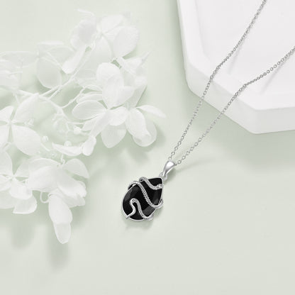 Silver necklace with a black pendant on a light background