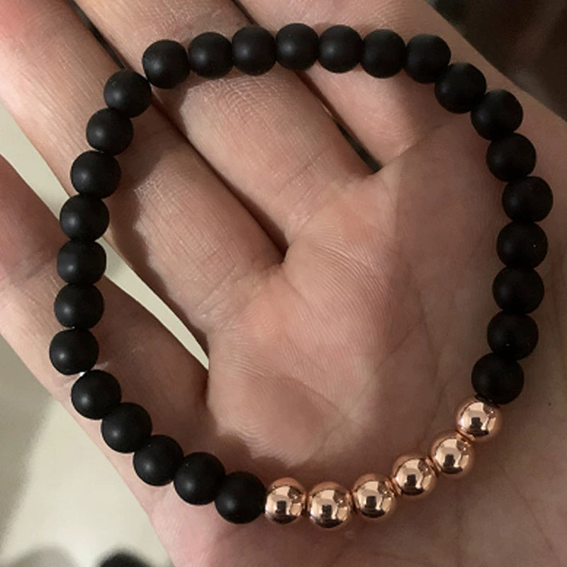 Black beaded bracelet with rose gold accents on a hand