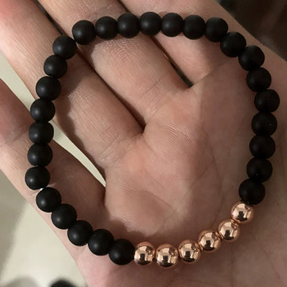 Black beaded bracelet with rose gold accents on a hand