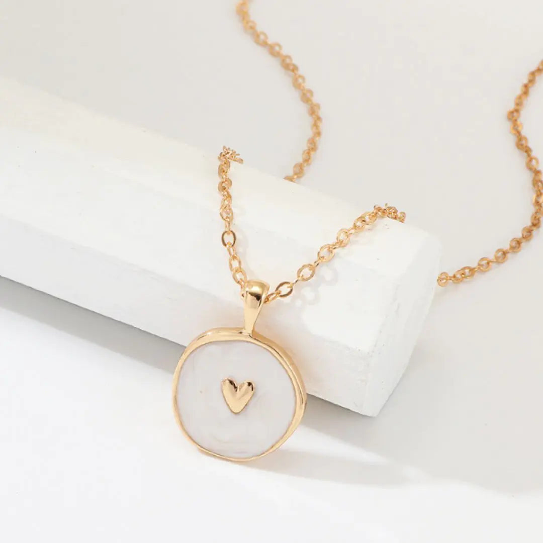 Gold necklace with a heart pendant on a white background