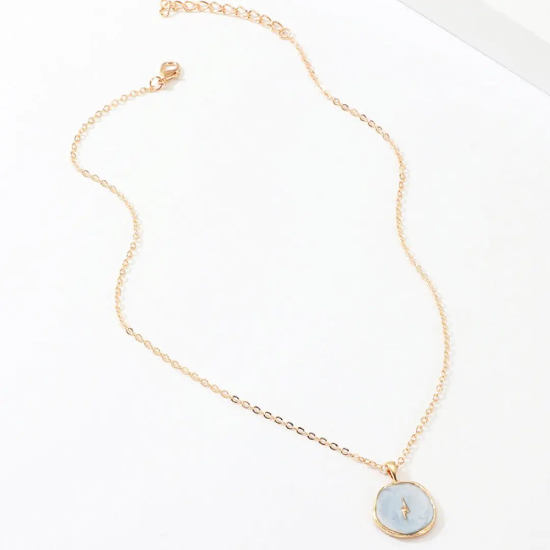 Gold necklace with a light blue pendant on a white background
