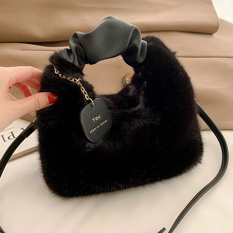 Black fluffy handbag with a heart-shaped tag held by a hand on a beige background