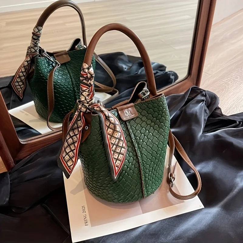 Green handbag with a decorative strap on a black surface