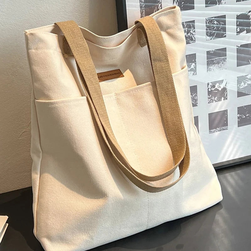 Beige tote bag with brown handles on a reflective surface