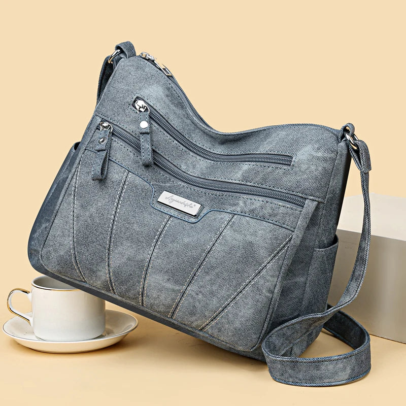 Gray shoulder bag with multiple zippers on a beige background