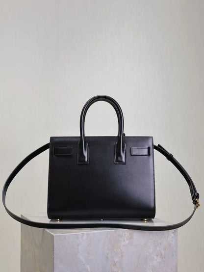 Black handbag on a clear stand against a light gray background