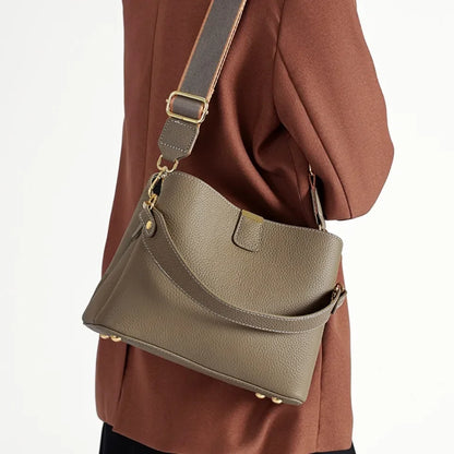Green handbag worn over one shoulder on a plain background