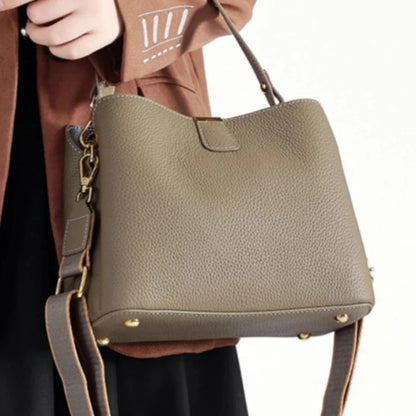 Person holding a beige handbag with 'MYH' branding.