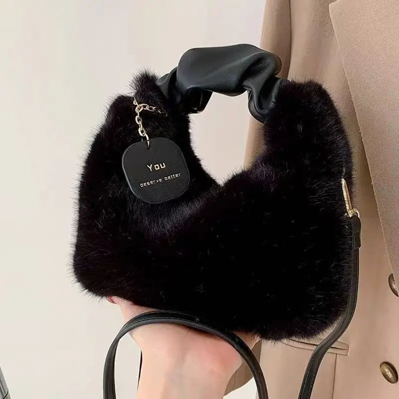 Black fur handbag held by a person wearing a beige coat.