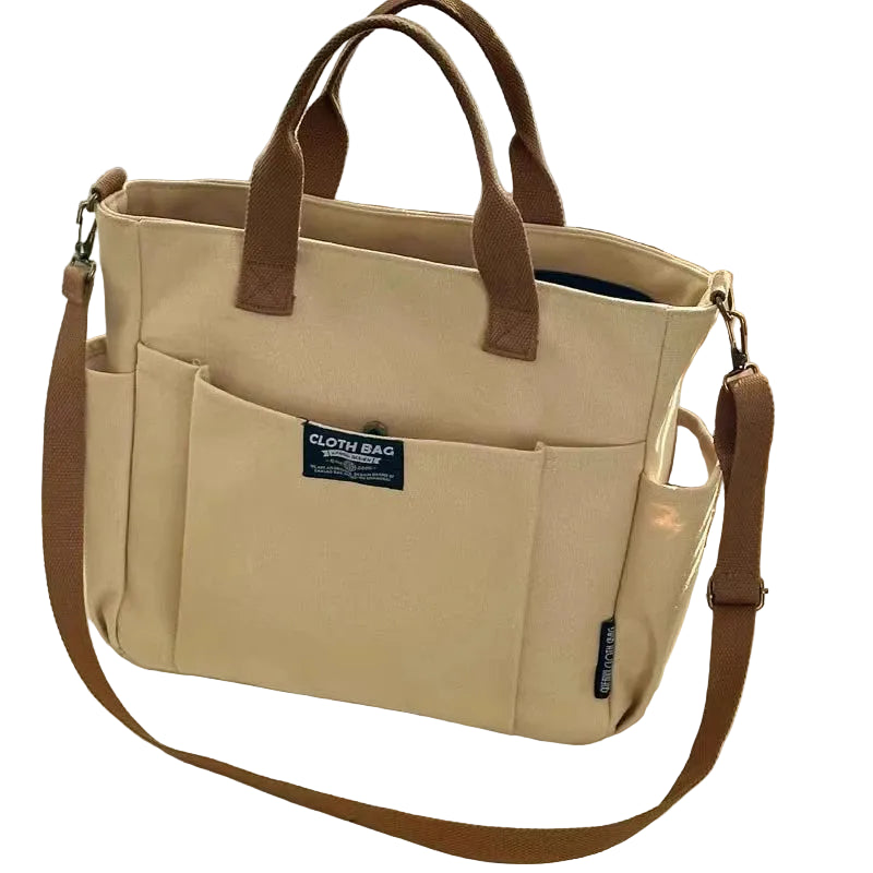 Beige tote bag with brown handles and strap on a light surface.