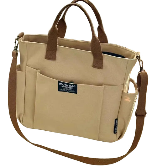 Beige tote bag with brown handles and strap on a light surface.