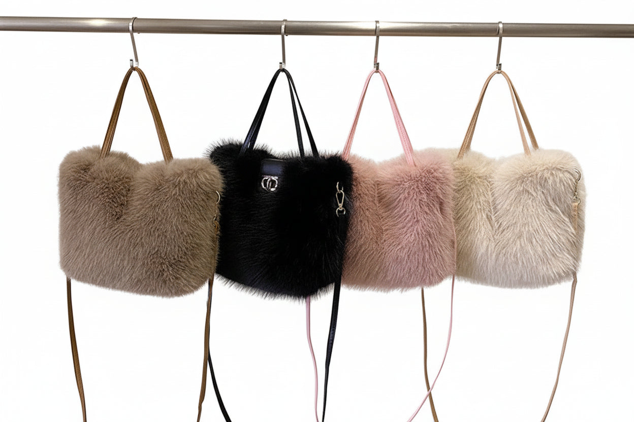 Four fur handbags in different colors hanging on a rack against a neutral background.