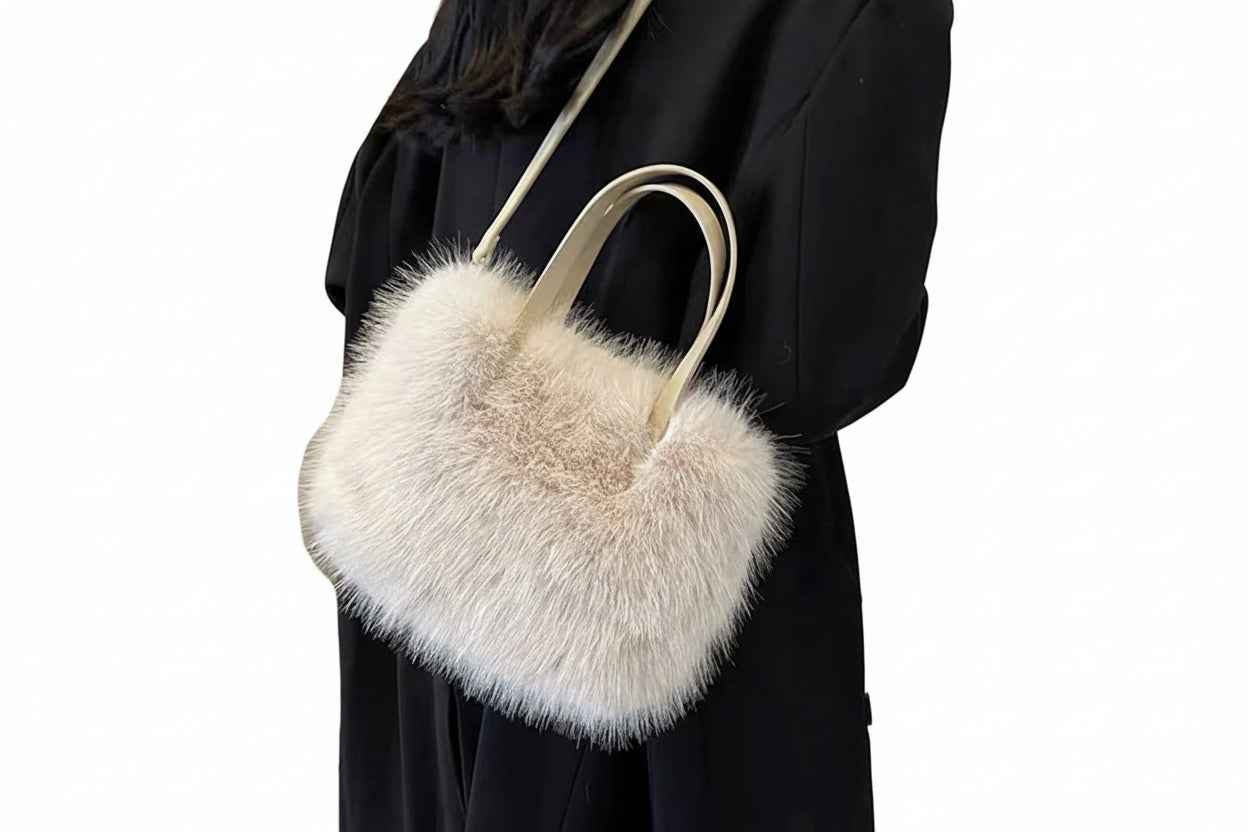 Person holding a fluffy beige handbag against a neutral background