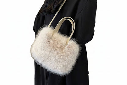 Person holding a fluffy beige handbag against a neutral background