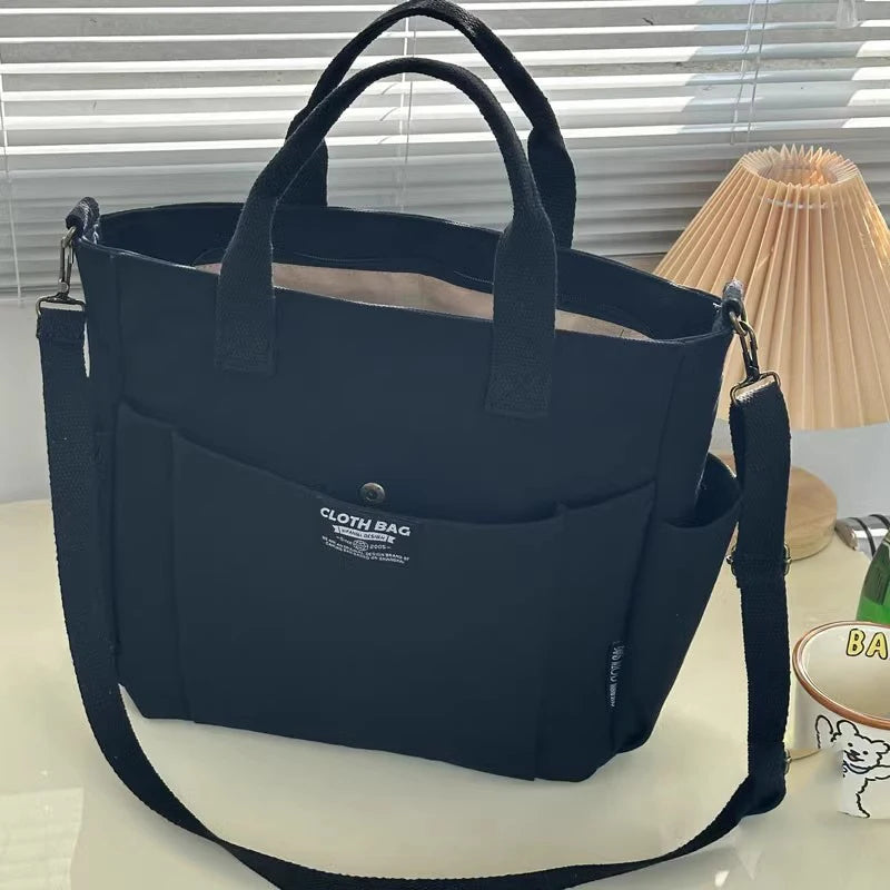 Navy blue tote bag with a strap on a light surface with a lamp in the background