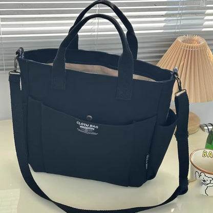 Navy blue tote bag with a strap on a light surface with a lamp in the background