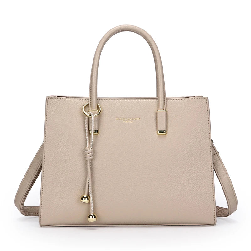 Beige apricot handbag with gold accents on a white background