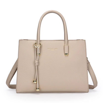 Beige apricot handbag with gold accents on a white background