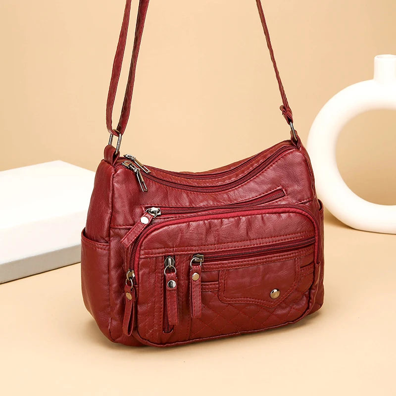 Red handbag with multiple zippers on a beige background