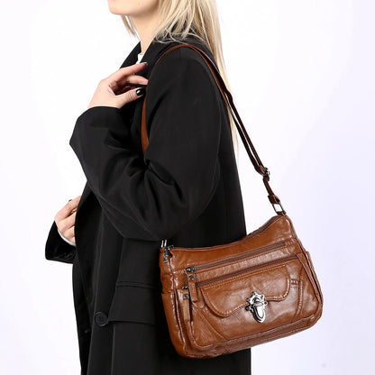 Brown leather handbag worn by a person on a white background