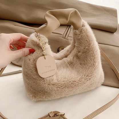 Beige fluffy handbag with a 'You are my sunshine' tag held by a hand.