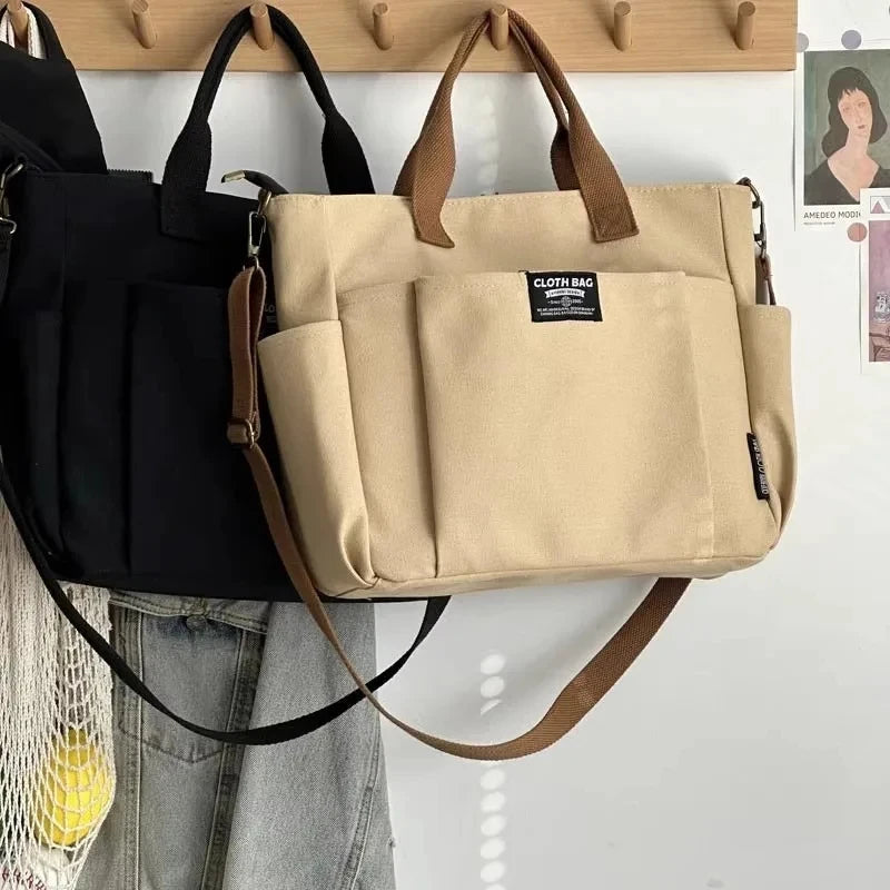 Beige bag with brown handles hanging on a wooden hook against a white wall.