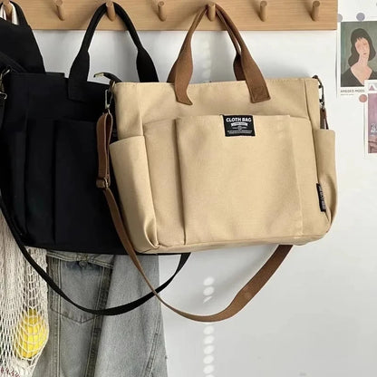 Beige bag with brown handles hanging on a wooden hook against a white wall.