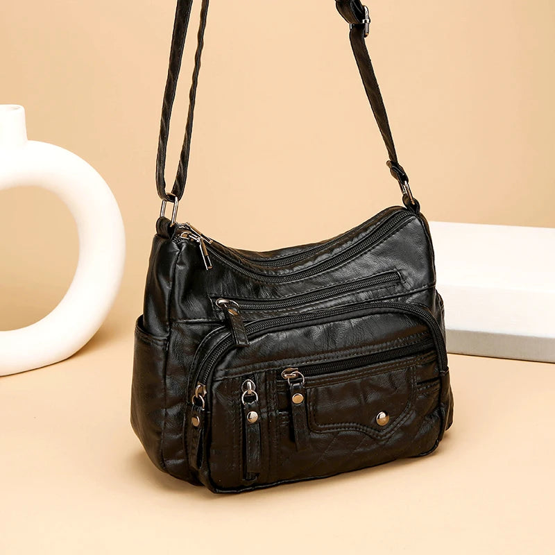 Black leather handbag with multiple pockets on a beige background