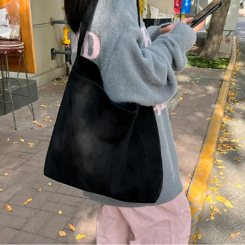 Person holding a black bag on a sidewalk with a blurred background