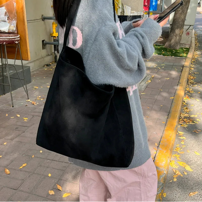 Person holding a black bag on a sidewalk with a blurred background