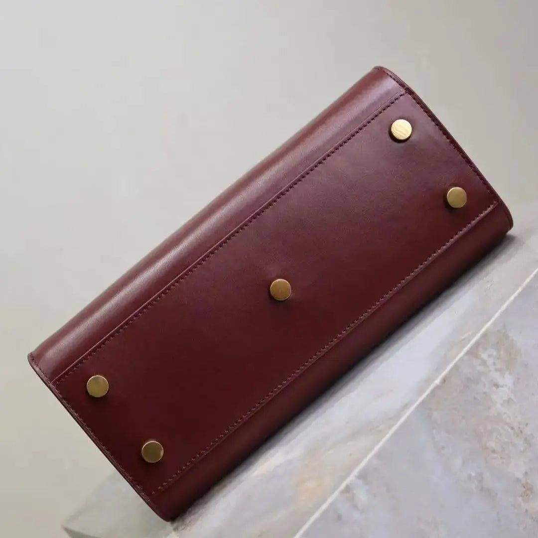 Brown leather wallet with gold studs on a light surface