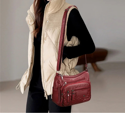 Person wearing a beige vest and holding a red handbag against a neutral background