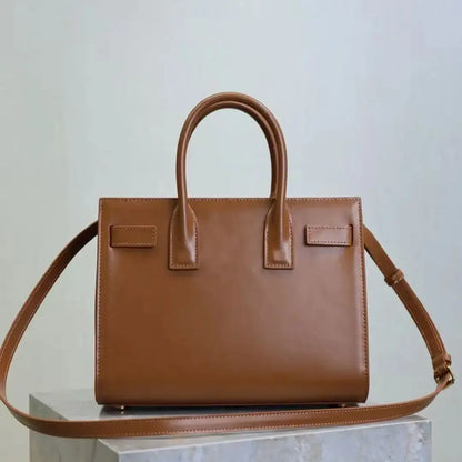 Brown handbag with a matching strap on a light gray background