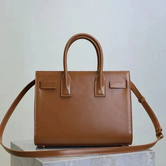 Brown handbag with a matching strap on a light gray background