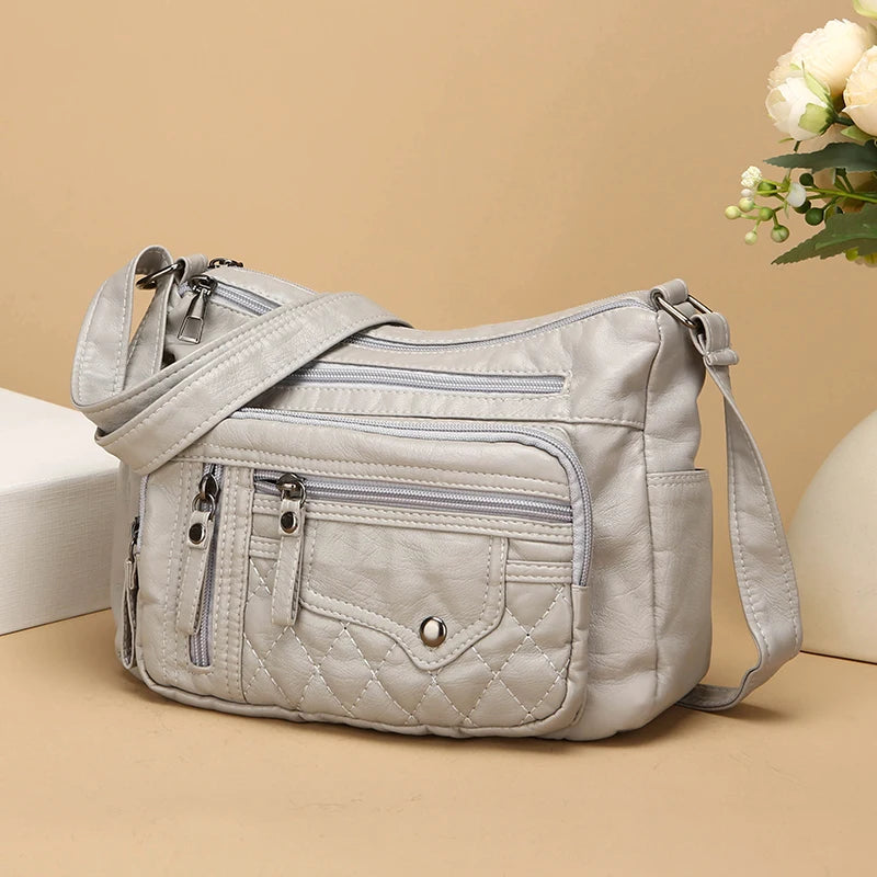 Light gray quilted handbag on a beige background with a decorative plant.