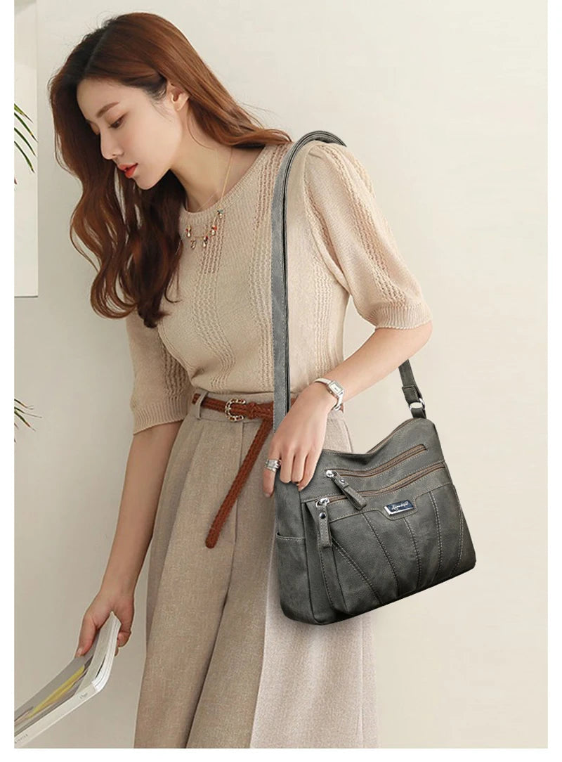 Woman holding a gray handbag against a plain background