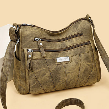 Brown leather handbag with multiple zippers on a beige background