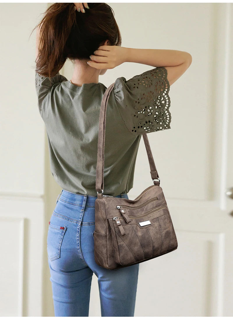Person wearing a green top and blue jeans with a brown handbag over their shoulder.