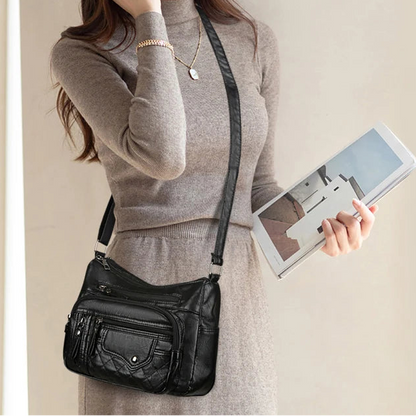 Woman holding a black shoulder bag and a tablet with a neutral background