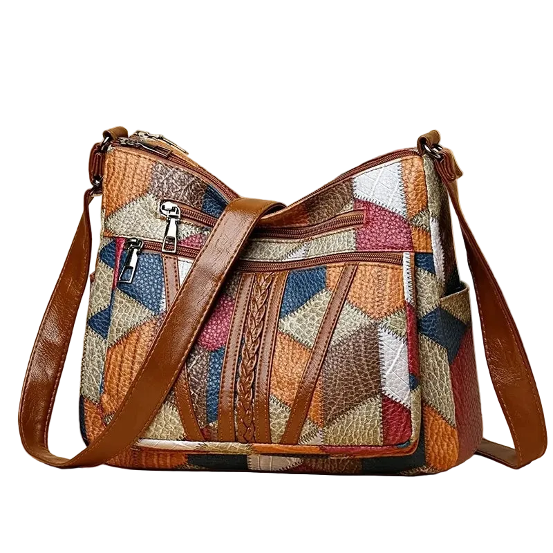 Multicolored patchwork handbag with brown leather straps on a white background