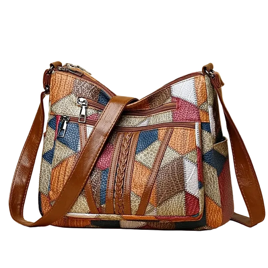 Multicolored patchwork handbag with brown leather straps on a white background