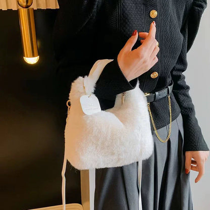 Person holding a white fluffy handbag with gold chain detail