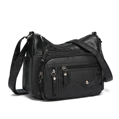 Black leather handbag with multiple pockets and zippers on a white background