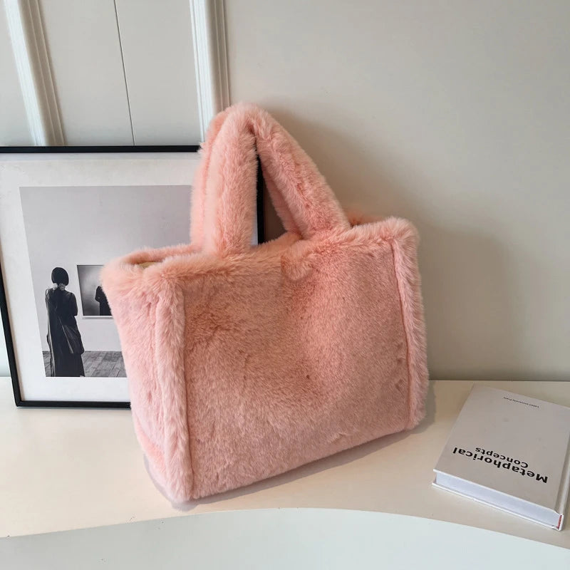 Pink fluffy handbag on a surface with a book and framed picture in the background